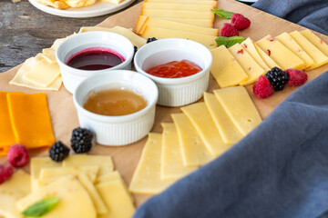 Assorted cheese platter featuring various cheese types, accompanied by colorful fruit garnishes and dipping sauces, creating an inviting and appetizing presentation for gatherings with copy space