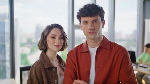 Two startupers smiling camera at corporate office closeup. Happy managers posing