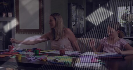 Crafting mother and daughters painting, cutting at home dining table, with paint jars and scissors
