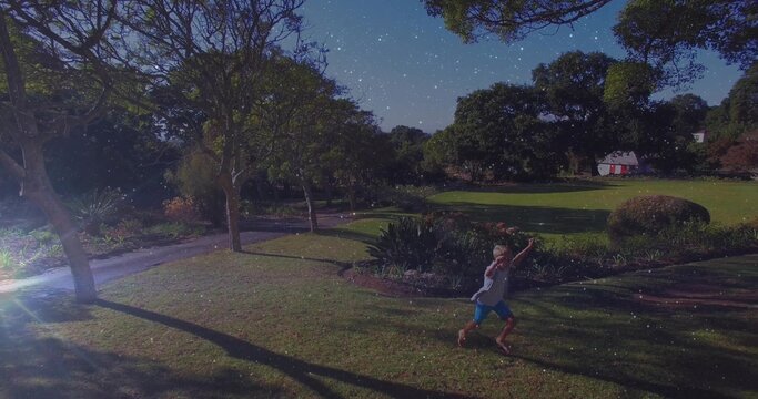 Naklejki Walking barefoot boy wearing blue shorts crossing path at park near cottage under stars, copy space