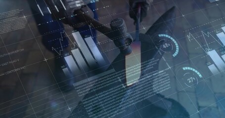 Adjusting scientist in lab coat, gloves turning microscope focus knob at bench with digital charts