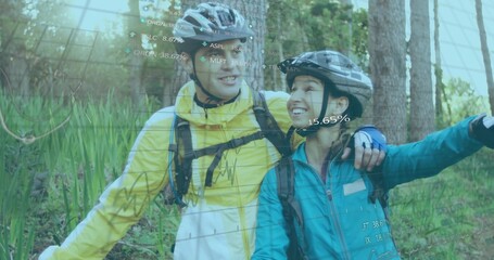 Smiling couple standing on forest path with helmets, backpacks, displaying AR data overlays