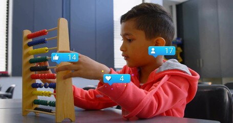 Counting boy wearing red sweatshirt moving beads on wooden abacus in classroom, with overlay icons
