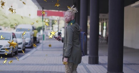 Standing light-skinned man glancing over shoulder on city sidewalk, with phone, gold star graphics