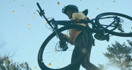 Hoisting cyclist lifting mountain bike overhead on trail, wearing reflective leggings and helmet