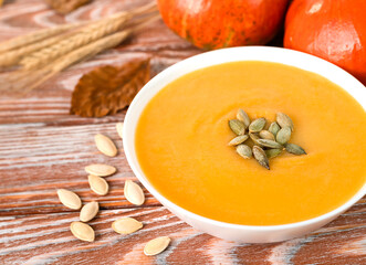 Delicious homemade pumpkin cream soup on the wooden table. Dietary dishes from seasonal vegetables. Close-up. Selective focus.