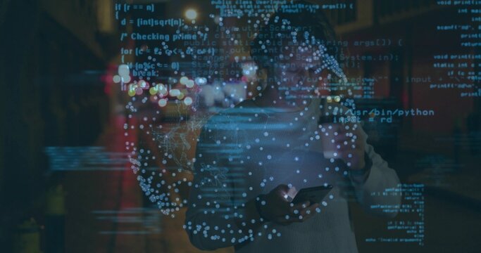 Holding smartphone, European man wearing sweater standing on street at night, with code overlay