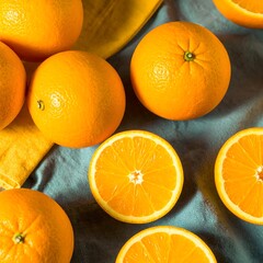 Fresh oranges, whole and sliced, on a textured surface