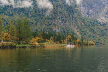 small boat docked at a lake pier on a rainy autumn day