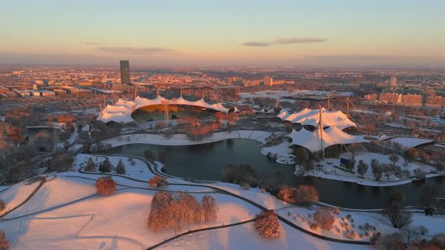 Aerial view of Munichs Olympic Park Bavaria Germany blanketed in snow featuring Olympiastadion Olympiahalle and Olympiaberg at sunrise Iconic winter cityscape