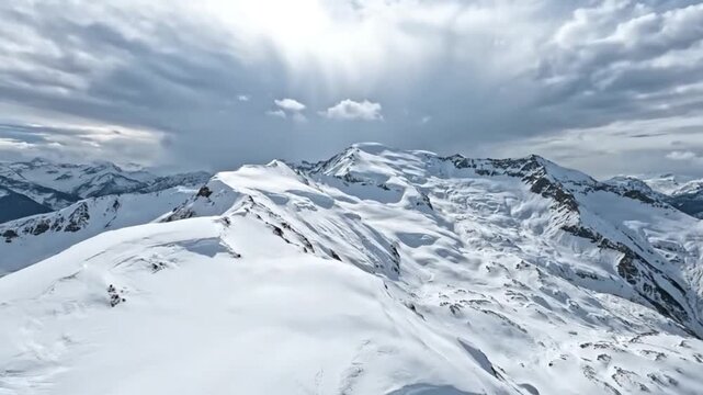A glorious winter day in the high mountains, with sunbeams illuminating a vast, snow-covered alpine landscape