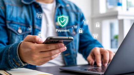 Man using secure payment app on phone while working on laptop computer