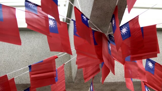 Slow motion of multiple Taiwan flags hanging under a concrete structure, symbolizing national pride in an urban setting.