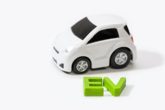 Concept of Electric vehicle created with toy models and green 3d printed text.