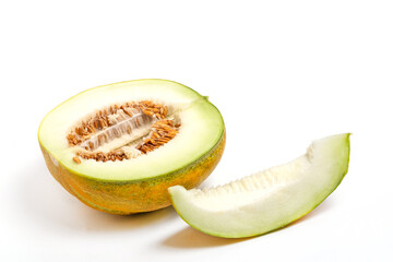 Halved cantaloupe melon with slice beside it. Melon has greenish yellow rind and light orange interior filled with seeds.