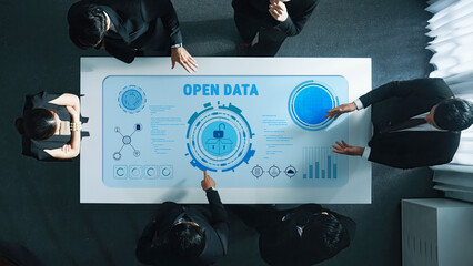 A diverse team engages in a business meeting focused on open data strategy, utilizing interactive technology for enhanced collaboration and communication in a modern office setting. Trope