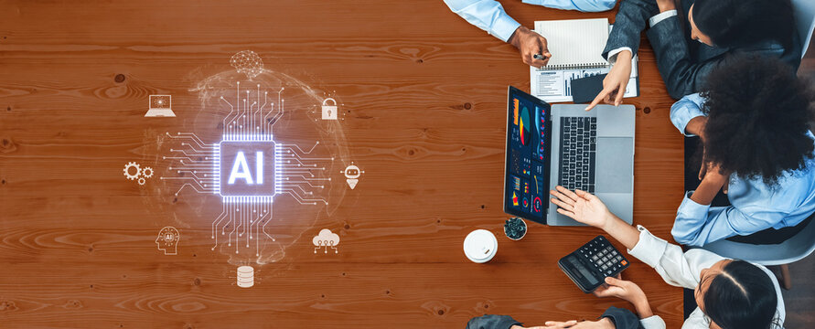 A diverse business team collaborates at a modern office table, exploring technology and artificial intelligence concepts using laptops and data charts. Trope - Powered by Adobe