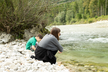 Children sitting on the coast near the river in the forest.