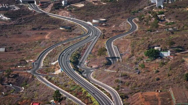 Tenerife, Canary Islands: Aerial view of cars navigating TF-1 highway through Tenerife's volcanic terrain, highlighting unique infrastructure transportation and natural scenery. Drone flight footage