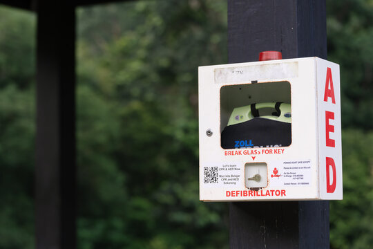 PENANG, MALAYSIA - Sep 19, 2025: Public outdoor defibrillator unit mounted on a pole with emergency access instructions.