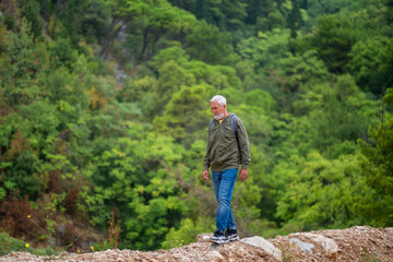 Naklejka premium Mindfulness. senior man peaceful mood hiking portrait in quiet forest senior man in green hoodie hiking portrait showing meditation relaxation and harmony with nature