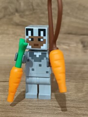 Obraz premium Whimsical block figures a pink pig-like character with a golden weapon and a grey animal holding a fresh carrot, posed on wood, symbolizing fantasy play and imaginative adventure