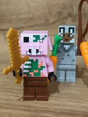 Fototapeta premium Whimsical block figures a pink pig-like character with a golden weapon and a grey animal holding a fresh carrot, posed on wood, symbolizing fantasy play and imaginative adventure