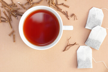 Liquorice root tea with roots and teabags on beige background, copy space, natural medicine, antiviral treatment, immune booster concept