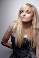 Naklejka premium A captivating portrait of a stylish woman with blonde hair, showcased in elegant studio lighting and wearing a sophisticated black dress that perfectly highlights her graceful features.