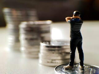 A small figurine of a person stands on a stack of coins