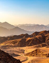 Naklejka premium A sweeping vista of a desert mountain range bathed in the warm hues of dawn.