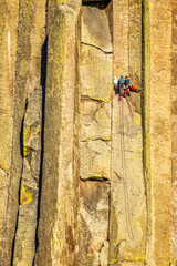 Unidentifiable team of rock climbers climb the Devils Tower wall in Crook County, Wyoming at sunset. Devils Tower in Wyoming is considered one of the best crack climbing areas in the world.