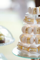 Pyramid of macarons with cream and golden details, wedding dessert table.
