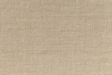 Close-up of natural beige paper like fabric reveals coarse weave, forming a tiny grid, creases and rough texture