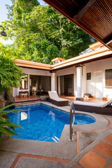 Private tropical pool with sun loungers and lush green surroundings