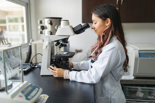 Female scientist using microscope in modern laboratory