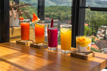 Colorful drinks on a wooden table with a scenic view.