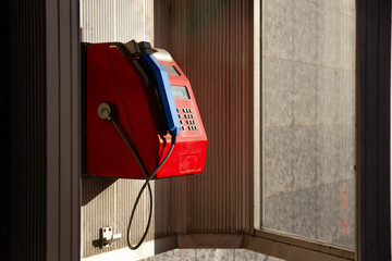 Retro Red Public Payphone With Blue Handset In Phone Booth In CIty
