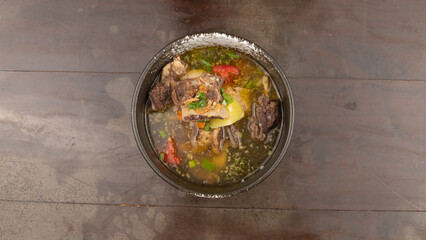 Overhead shot of a bowl of beef stew on a wooden table.