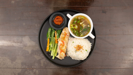 Overhead shot of a plate with rice, chicken, vegetables, soup, and sauce.