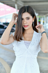 A young woman poses elegantly outdoors, showcasing her fashionable style and confidence.