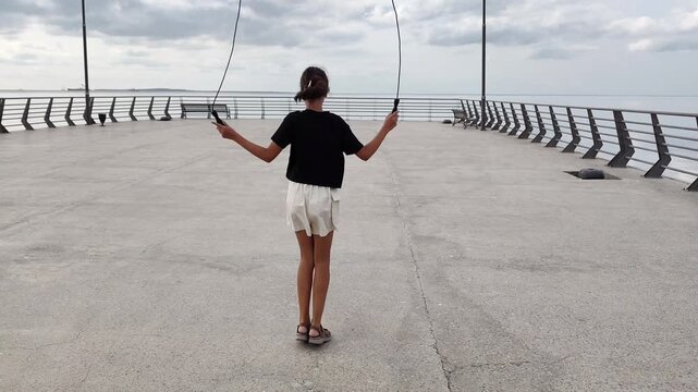 Teenage girl is jumping the robe on the seaside . High quality 4k footage