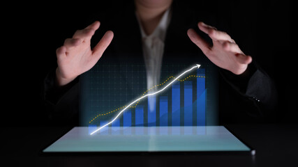 A business professional showcases an interactive hologram of a growth trend in a dark space, illustrating innovation and strategic planning using modern technology. Impute