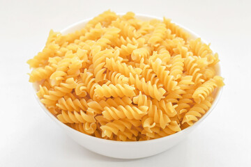 Fusilli pasta in a white bowl. Uncooked Italian food.