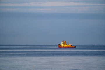 Yellow workboat on calm blue sea with wide copy space, minimal seascape