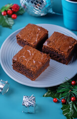 Dark chocolate brownie cakes in a plate on a blue background for Christmas holidays
