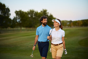 Happy golfing couple walking on golf course.