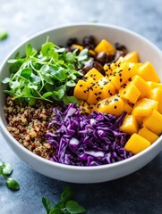 Bright and colorful quinoa salad bowl with mango, purple cabbage, and greens served on a simple gray background