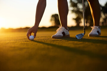 Close up of player preparing to take shot on golf course at sunset. © Drazen