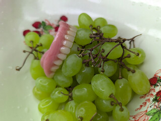 Denture on grapes inside a plate